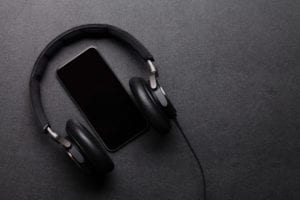 Black Headphones and smartphone on leather desk table