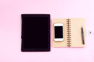 Notebooks, tablet, pen and smart phone on a pastel pink background